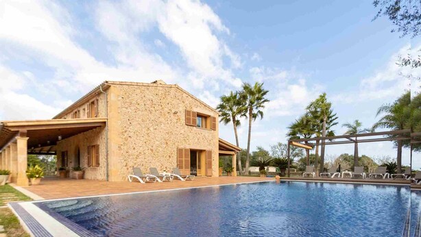 A stone building with a pool and lounge chairs.