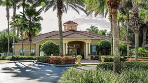 A hotel with a Mediterranean-style facade, a central entrance with a portico, and a well-maintained garden with palm trees and shrubs. - 4 Bed/3 Bath 3 Miles from Disney World in Emerald Island Resort (Kissimmee)