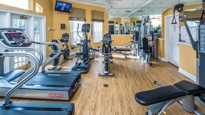 Un gimnasio con cintas de correr, elípticas y equipo de pesas.