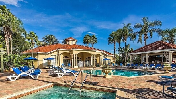 Un área de piscina con sillones de descanso, un jacuzzi y un pabellón cubierto.