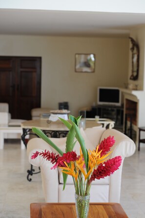 Una sala de estar con un sofá blanco, una mesa de centro de madera y un jarrón con flores.