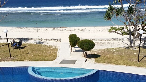 A swimming pool with a view of the ocean and beach.