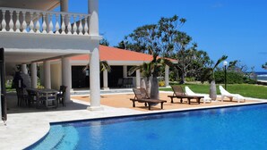 A pool area with lounge chairs and a covered seating area.