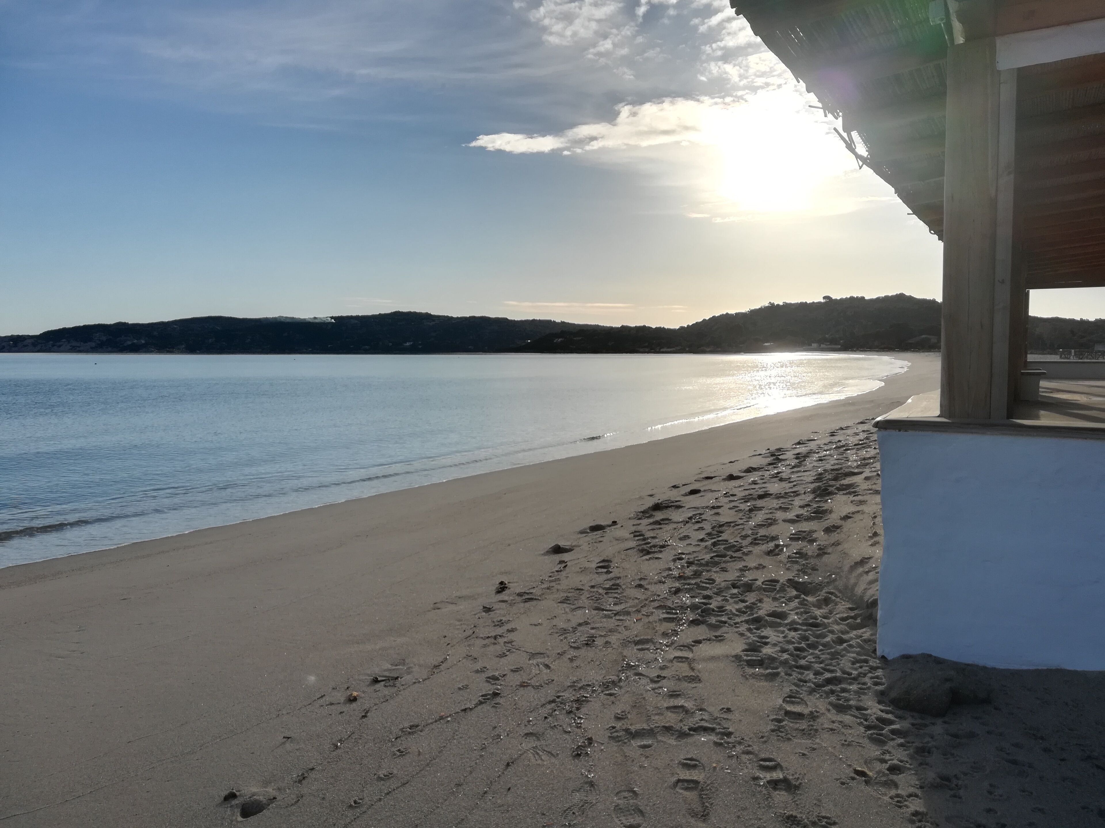 A beach with footprints leading to a building with a wooden structure.