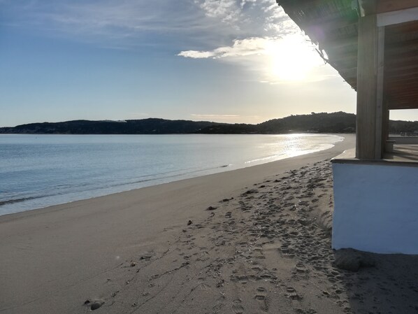 A beach with footprints leading to a building with a wooden structure.