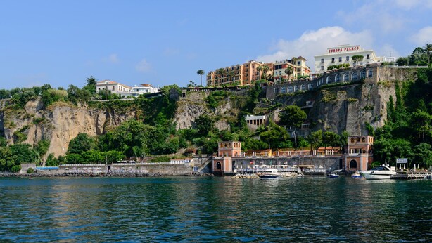 A coastal hotel with multiple buildings on a cliff, overlooking the sea.