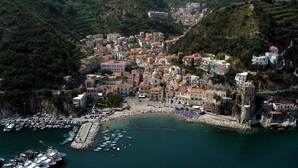 A coastal town with terraced buildings, a marina, and a beach.