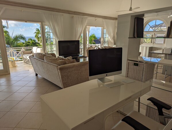 A spacious living area with a large flat-screen TV, a comfortable sofa, and a dining area with a high table and chairs. - A Luxurious Place To Chill Out In Barbados (Mount Standfast)
