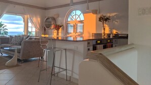 A modern kitchen with a central island, bar stools, and a seating area with a sofa and chairs. - A Luxurious Place To Chill Out In Barbados (Mount Standfast)