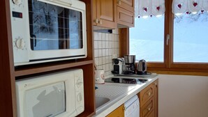 A compact kitchen with wooden cabinets, a microwave, a toaster, and a dishwasher.
