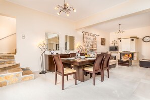 Un vaste espace dédié à la salle à manger, avec une grande table en bois, de nombreuses chaises et une cheminée.
