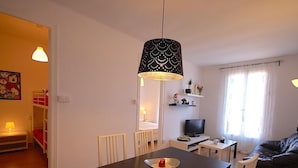 A compact living space with a dining table, a sofa, a TV, and a small kitchen area. - APARTMENT BARCELONA near BEACH (Barcelona)