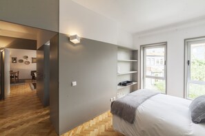 A modern bedroom with a bed, built-in shelves, and a view of the outside.