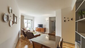 A modern living room with a dining area, a TV, and a bookshelf. - CdC II Apartments By Tale House (Porto)