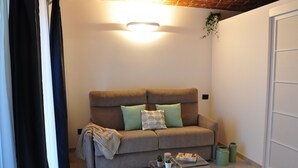 Uma sala de estar aconchegante com um sofá, uma mesa de centro e uma planta pendurada.