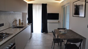 Cozinha moderna com fogão embutido, pia e área de jantar com mesa e cadeiras.