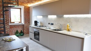 Uma cozinha moderna com parede de tijolos, uma janela e um espaço de refeições com mesa e cadeiras.