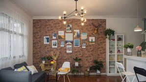 Ein Wohnzimmer mit Backsteinwand, einer Chandelier, einem Sofa, einem Esstisch und einem Bücherregal.