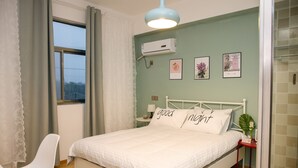Ein aufgeräumtes Schlafzimmer mit Bett, Nachttisch, Stuhl und einem Fenster mit Vorhängen.