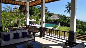 A covered outdoor seating area with a pool and lush greenery. - Exclusive 5 star villa with 365 ° view of the sea, mountains and rice fields! (Kayu Putih)