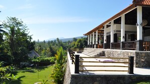 A resort with a stone staircase leading to a covered area, surrounded by lush greenery and a view of distant mountains. - Exclusive 5 star villa with 365 ° view of the sea, mountains and rice fields! (Kayu Putih)