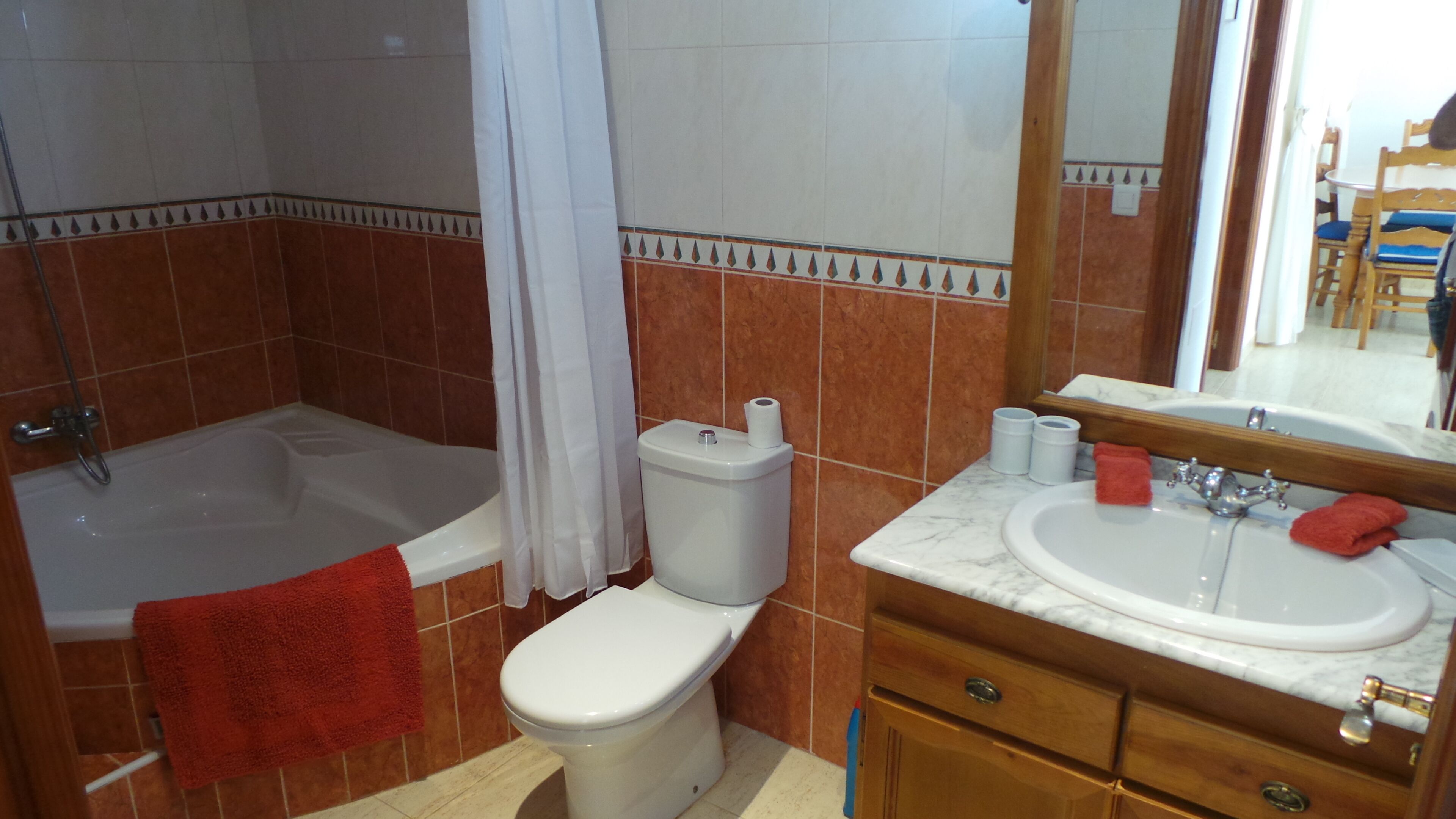 Et badeværelse med badekar, toilet og håndvask.