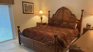 Een slaapkamer met een groot bed, een nachtkastje, een lamp, een klok en een ingelijste foto aan de muur.