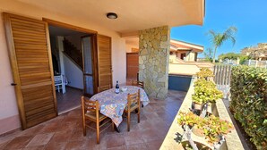 A patio with a table and chairs, a stone pillar, and potted plants. - WELL-LIT MEDITERRANEAN VILLA WITH VERANDA AND GARDEN ONLY 50 METERS FROM THE SEA (Campofelice PA, Italia)
