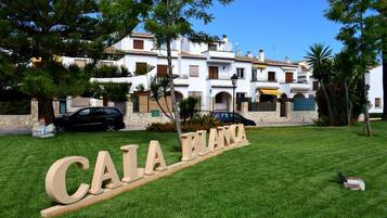 A sign reading "CALA BLANCA" in a well-maintained lawn area with a white building in the background.