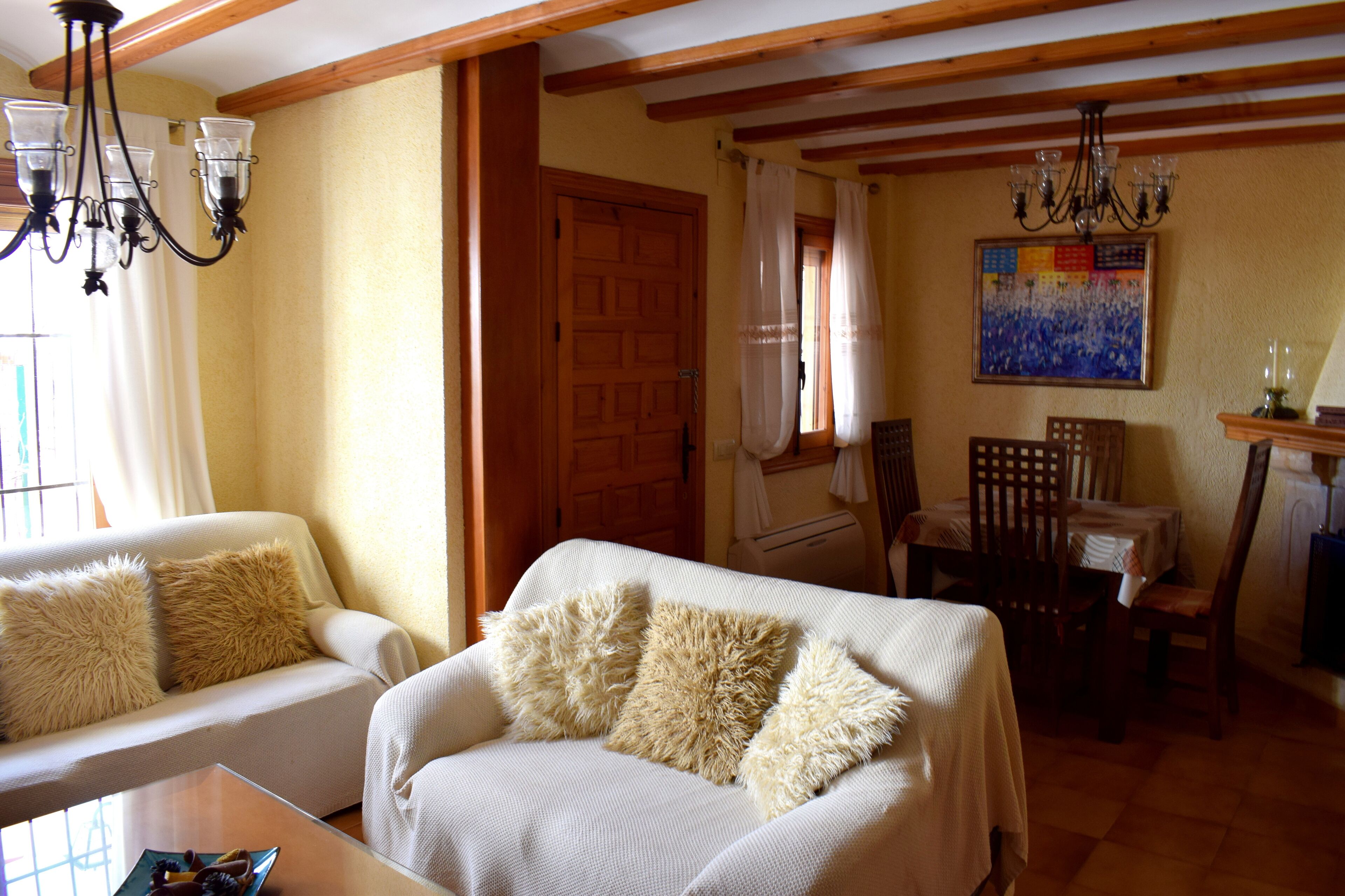 A cozy living room with a sofa, a coffee table, and a dining area with chairs and a table.