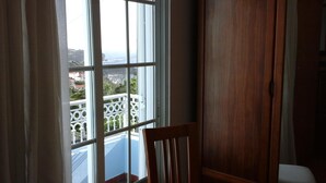 Une pièce dotée d’une grande fenêtre donnant sur un balcon avec une balustrade blanche.