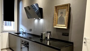 Une cuisine moderne dotée d’un élégant plan de travail noir, d’appareils électroménagers en acier inoxydable et d’un téléviseur à écran plat fixé au mur.