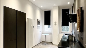 Une cuisine moderne avec un plan de travail foncé, des murs blancs et des spots encastrés au plafond.