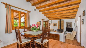 Un coin repas avec une table en bois, des chaises et une fenêtre agrémentée de rideaux.