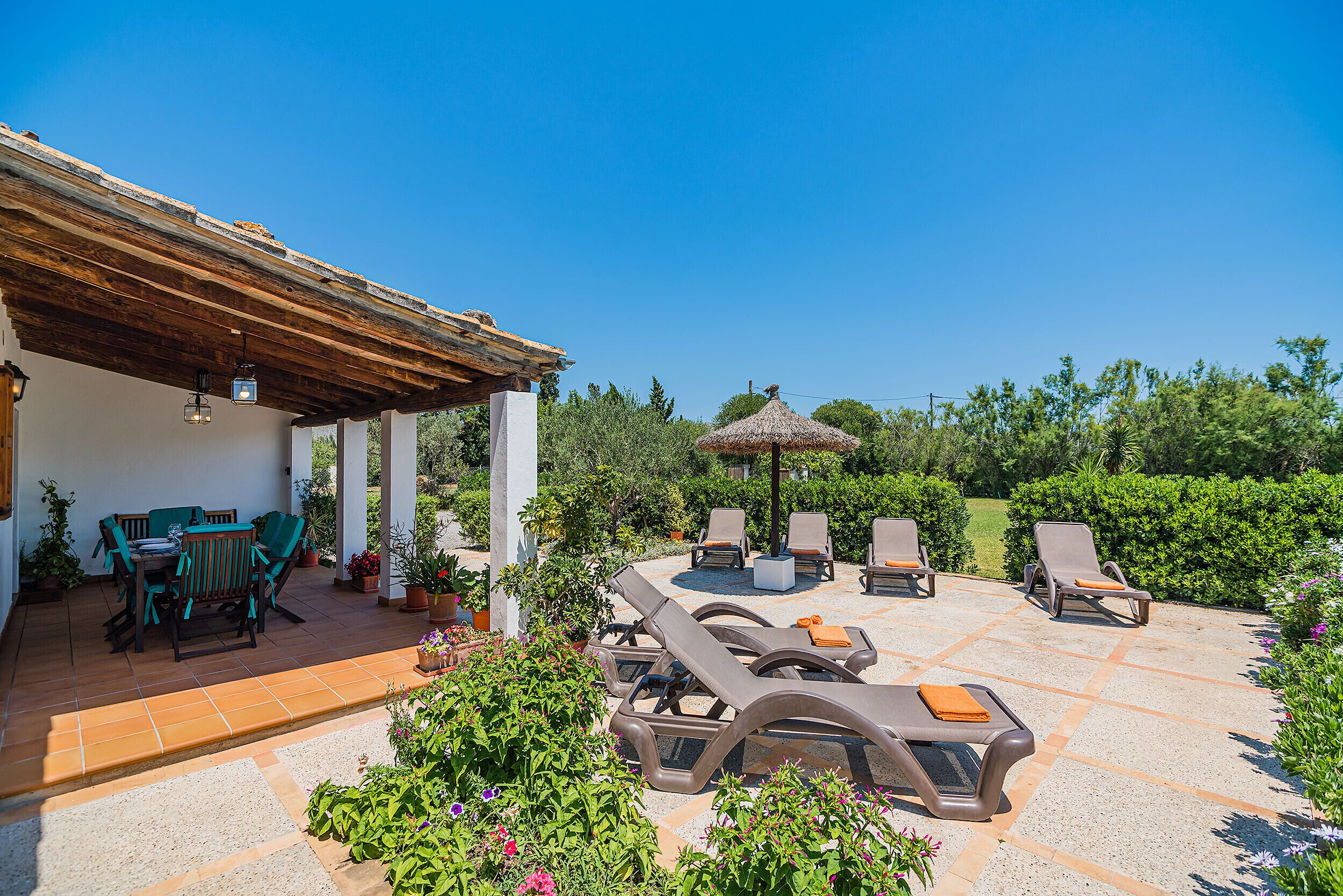 A patio with lounge chairs, a table, and a pergola.