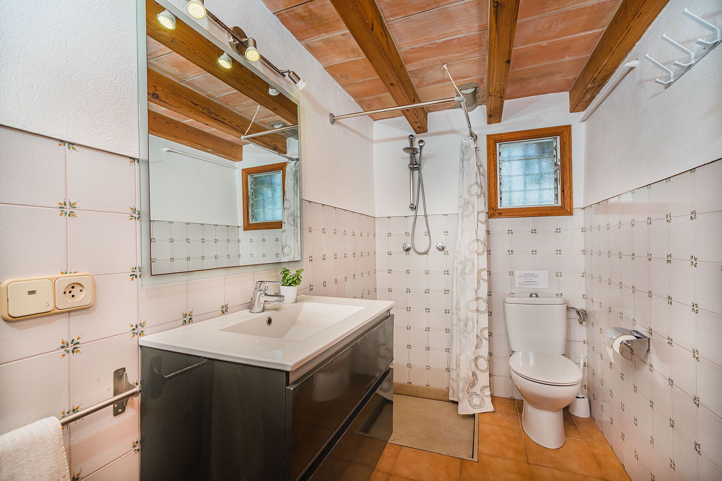 Une salle de bain avec un lavabo blanc, un miroir, une douche et des toilettes.