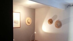 Une chambre à coucher avec un lit, une table de chevet, une lampe et deux chapeaux accrochés au mur.