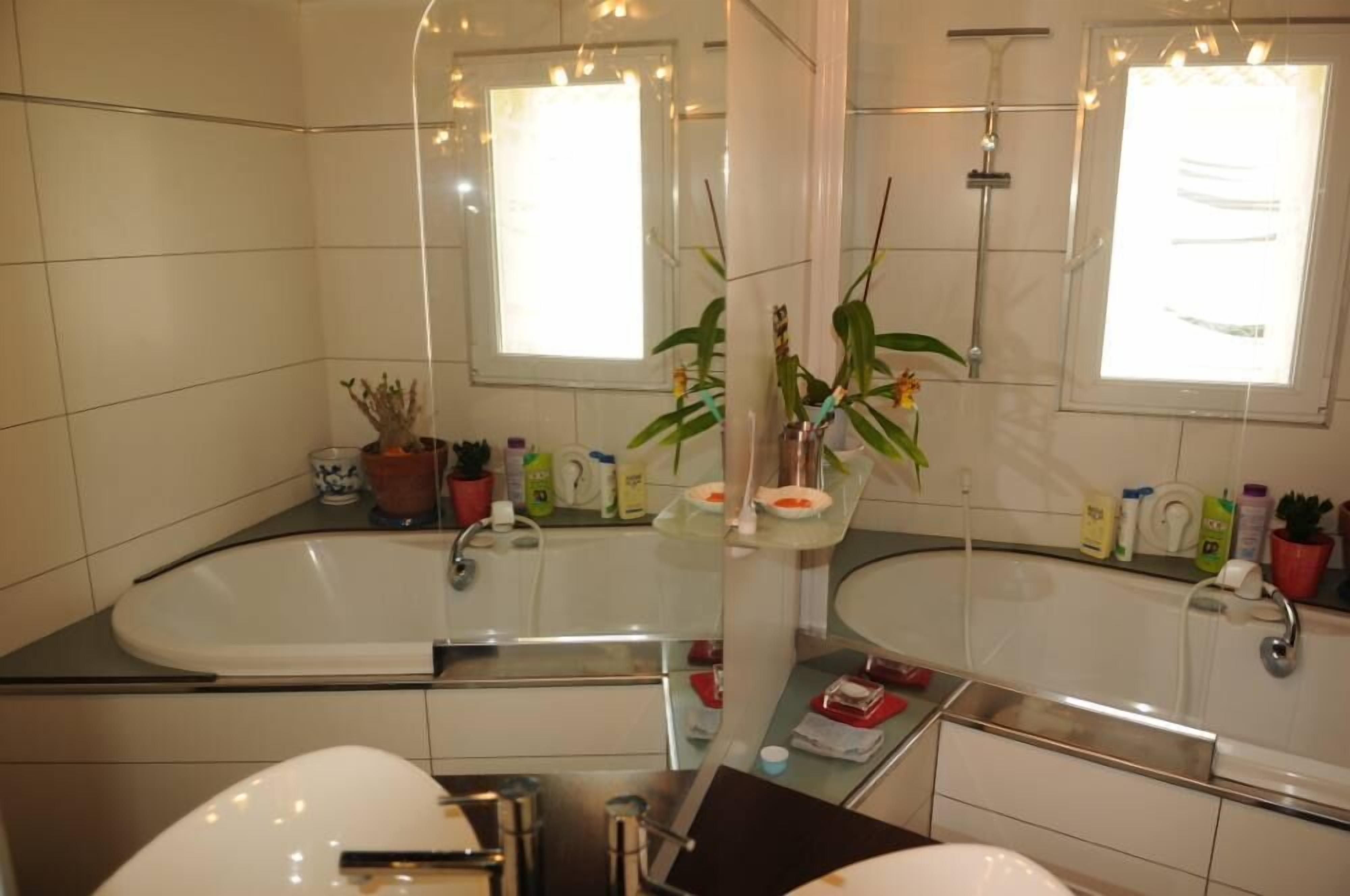 A modern bathroom with a large bathtub, a separate sink, and a mirror above the sink.