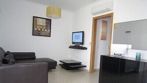 A modern living room with a sofa, a flat-screen TV, a small table, and a cabinet. - Duplex apartment in the center of town with swimming pool, 3 bedrooms, for 6 (tavira)