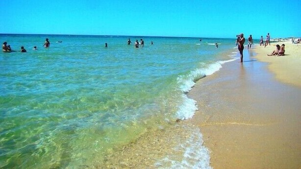 A beach with clear water, people swimming and walking along the shore. - Duplex apartment in the center of town with swimming pool, 3 bedrooms, for 6 (tavira)