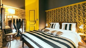 A hotel room with a bed, a chair, a lamp, and a patterned wall. - Charming Gite in Medieval Village 1mn walk to Shops & Restaurants (Nolay)