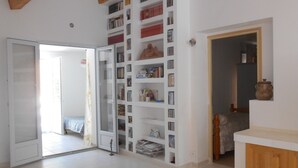 A spacious room with a large bookshelf filled with books and DVDs, a wooden cabinet, and a bed with a floral bedspread. -  part of villa on the ground floor next to a vineyard (Lorgues)