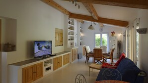 A living room with a television, wooden cabinets, a dining area with chairs, and a sofa. -  part of villa on the ground floor next to a vineyard (Lorgues)