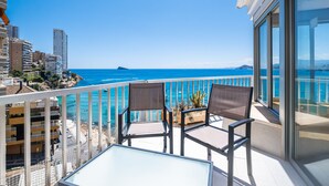 A balcony with two chairs and a table, overlooking a coastal cityscape and the sea. - Almadraba Penthouse (Benidorm)