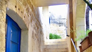 Una escalera estrecha con una puerta azul a la izquierda y una barandilla de metal a la derecha.