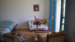 Ein Wohnzimmer mit einer Couch, zwei Sesseln, einem Couchtisch und einem Bett.