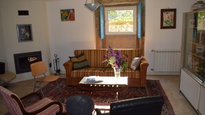 Ein Wohnzimmer mit einer Couch, Sesseln, einem Couchtisch mit einer Vase, einem Kamin und einer Heizung.