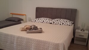 Een keurig opgemaakt bed met een gewatteerde dekbedovertrek, een nachtkastje met een lamp en een zacht vloerkleed.