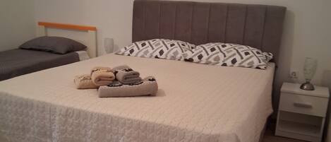 A neatly made bed with a quilted cover, a bedside table with a lamp, and a fluffy rug on the floor.