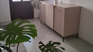 Een kamer met een deur, een kast en twee grote planten.